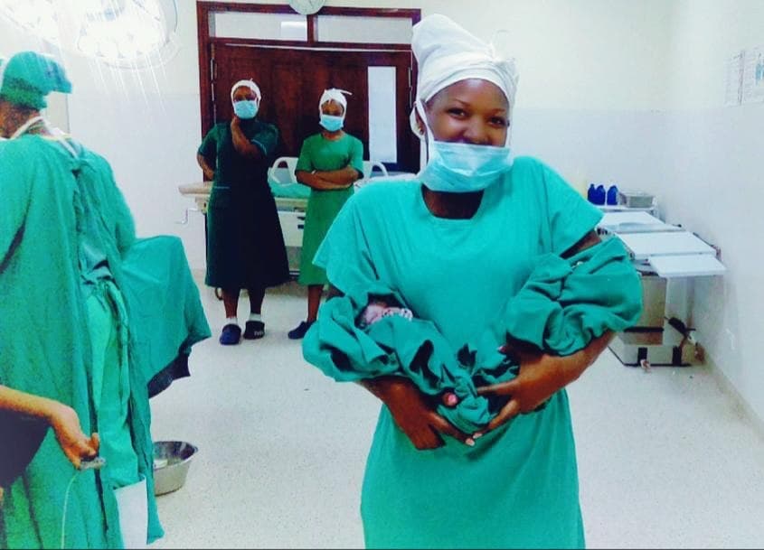 Margaret Birungi holding a newborn baby in a delivery room