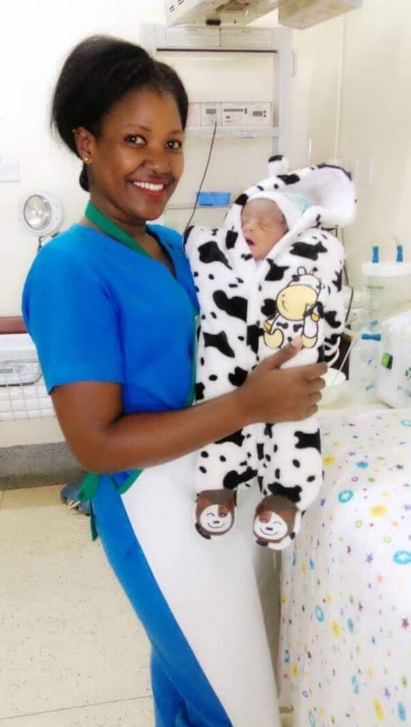 Midwife Margaret Birungi holding a newborn baby